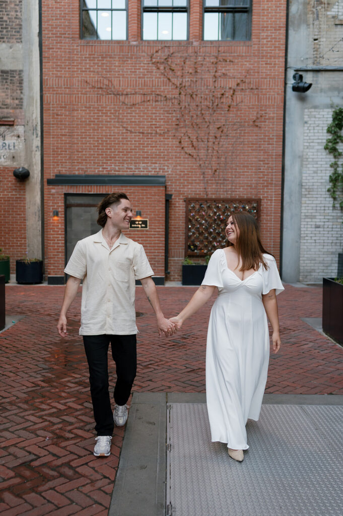 Couple holding hands and walking together in The Belt during their downtown Detroit engagement photos.
