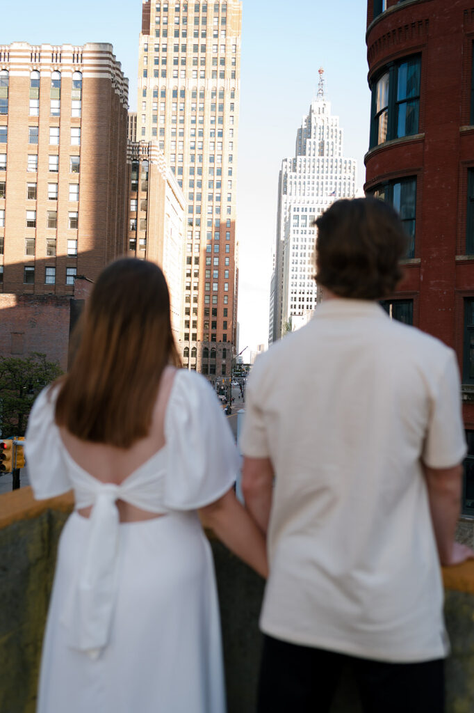 Couple looking out at the downtown Detroit skyline during their engagement photos.