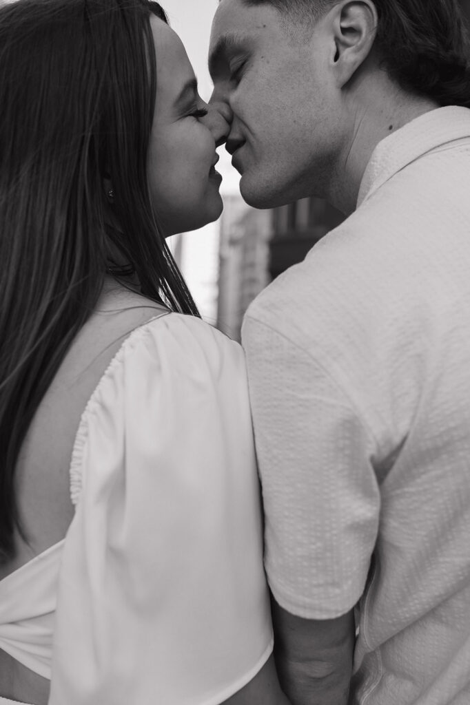 Close up black and white photo of a couple going in for a kiss.