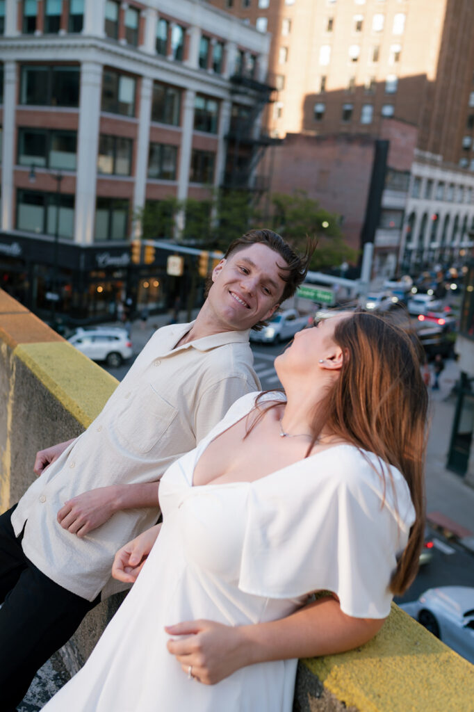 Couple leaning on a rooftop ledge during their downtown Detroit engagement session.