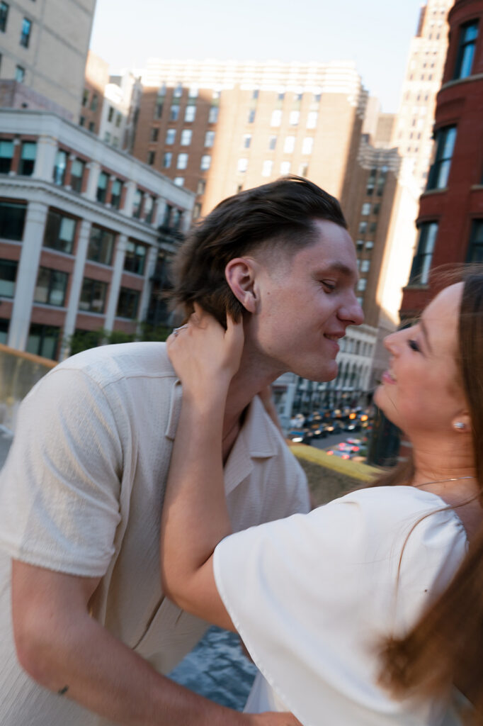 Couple going in for a kiss during their rooftop engagement photos in Detroit.