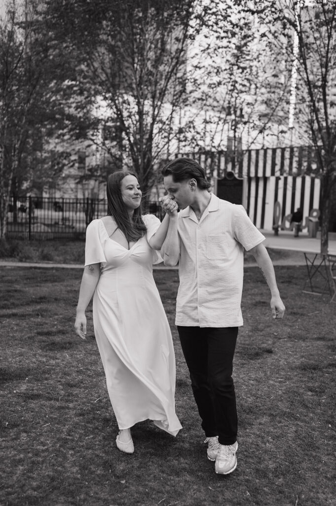 Black and white photo of a man kissing his fiancés hand in downtown Detroit. 