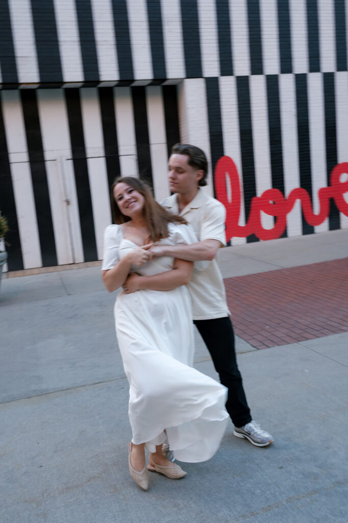 Couple moving together in front of a black and white striped wall during their Detroit engagement photos.