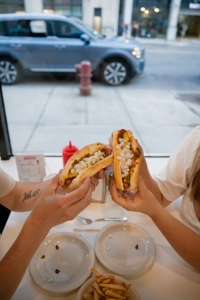Couple toasting coney dogs inside American Coney Island during their downtown Detroit engagement photos.