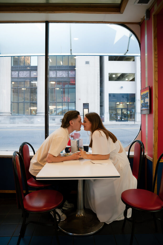 Couple leaning across the table for a kiss inside American Coney Island.