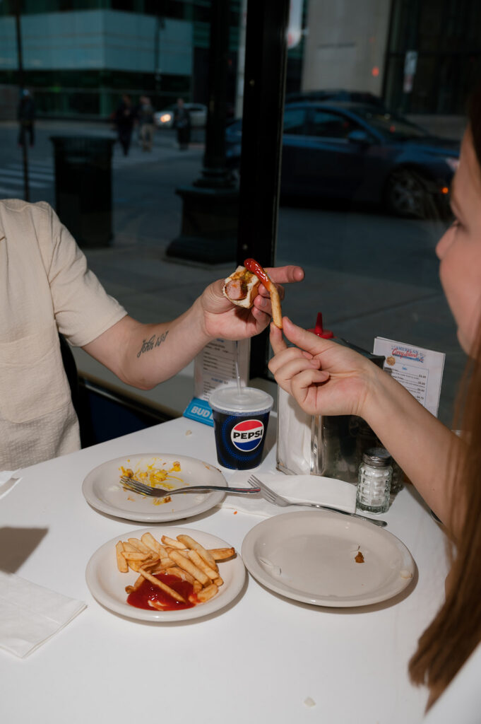 Flash photo of a couple sharing fries at American Coney Island during their downtown Detroit engagement session.