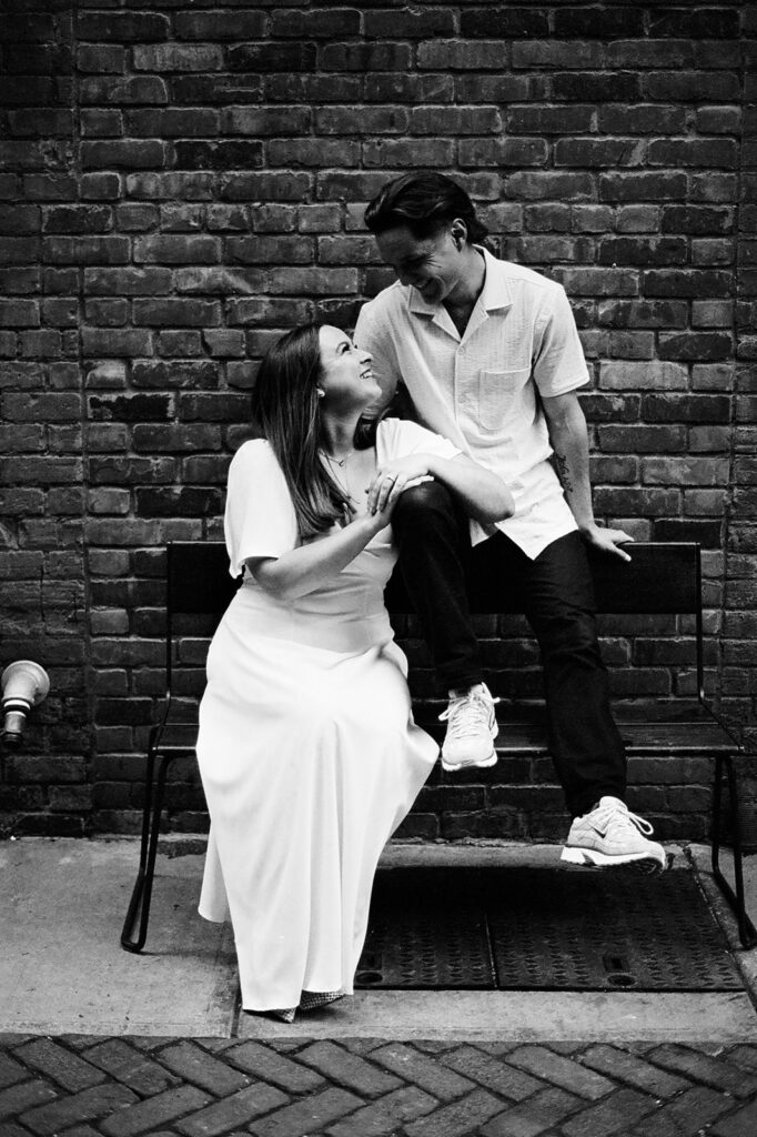 Black and white 35mm film photo of a couple sitting in an alleyway together.