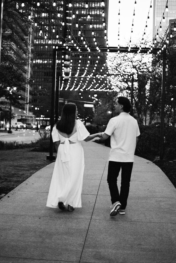 Black and white 35mm film photo of a couple walking under string lights in downtown Detroit.