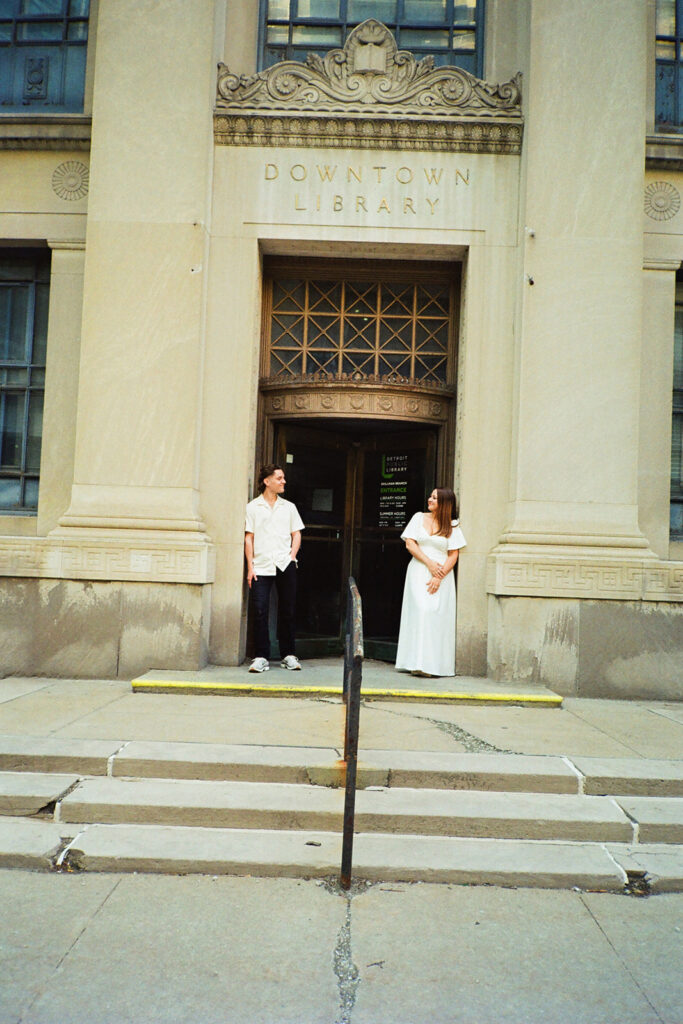 35mm film photo of a couple posing in front of the Downton Library in Detroit. 