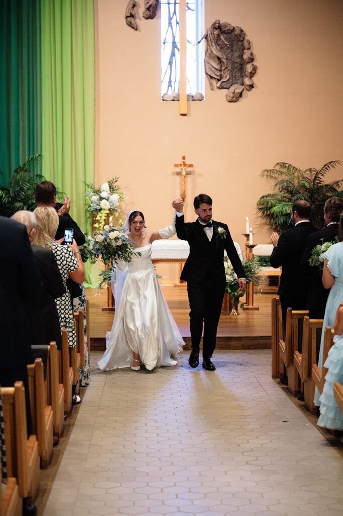 Bride and groom walking back down the aisle as husband and wife after their Catholic wedding ceremony at St. Edith Catholic Church in Livonia.