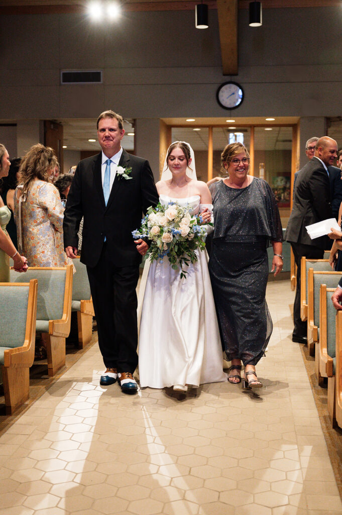 Bride walking down the aisle with her parents for her Catholic wedding ceremony at St. Edith Catholic Church in Livonia.