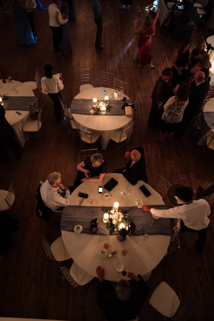 Overhead shot of guests talking at tables during a wedding reception.