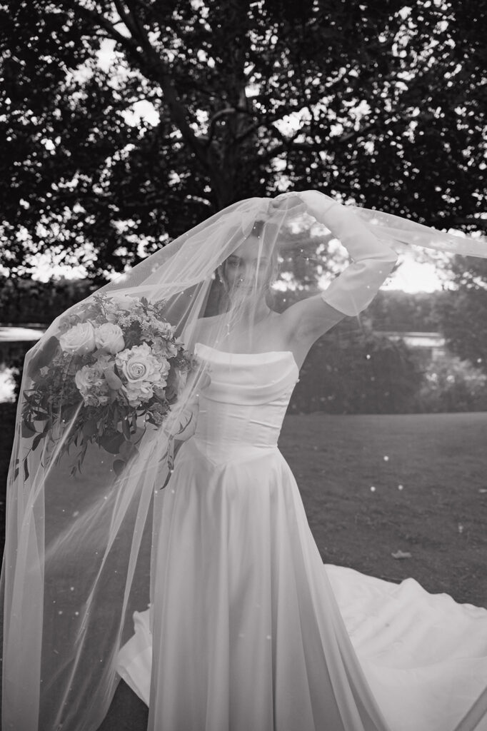 Dramatic black and white portrait of a bride posing under her veil.