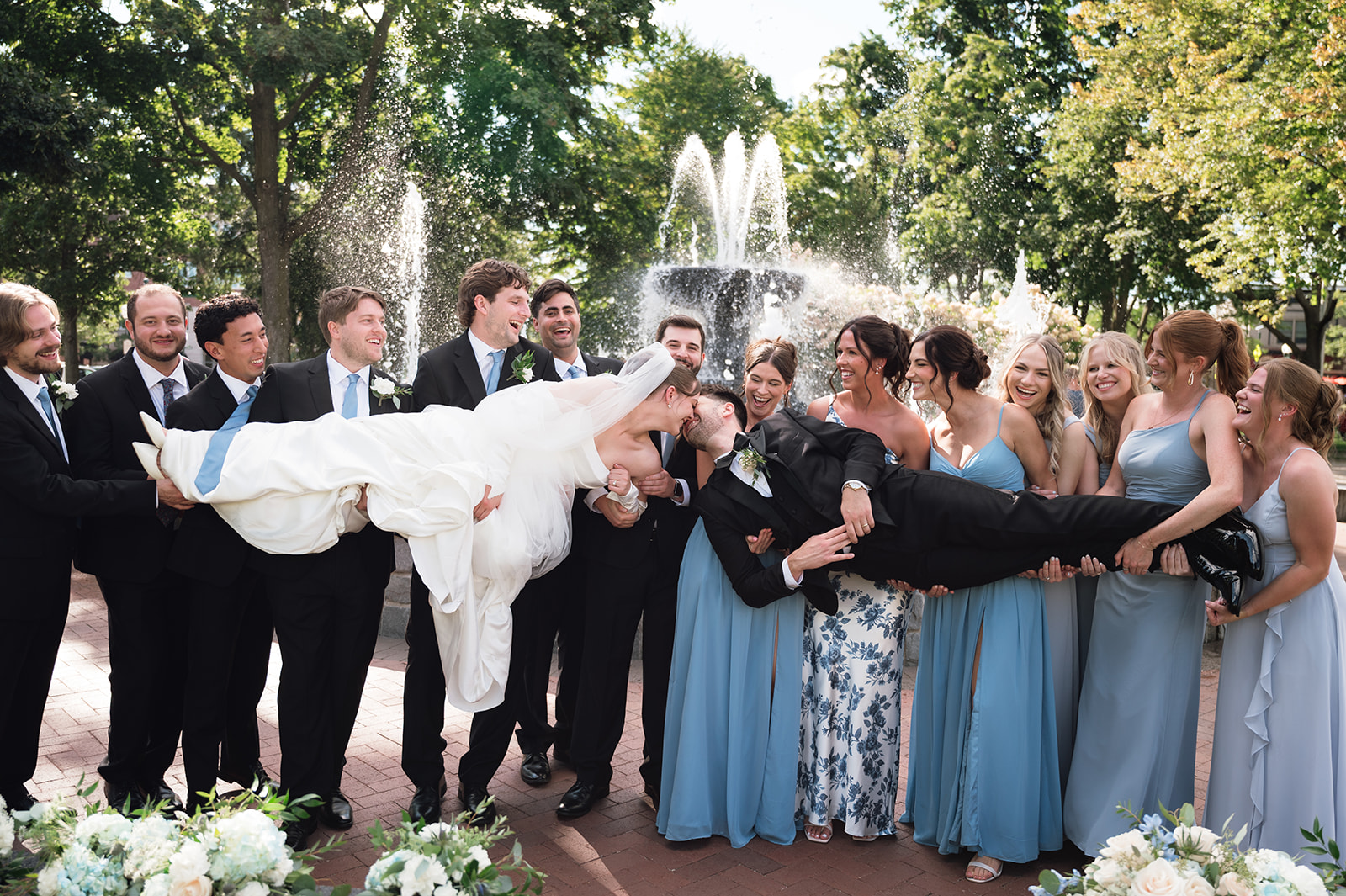 Wedding party holding the bride and groom up as they kiss.