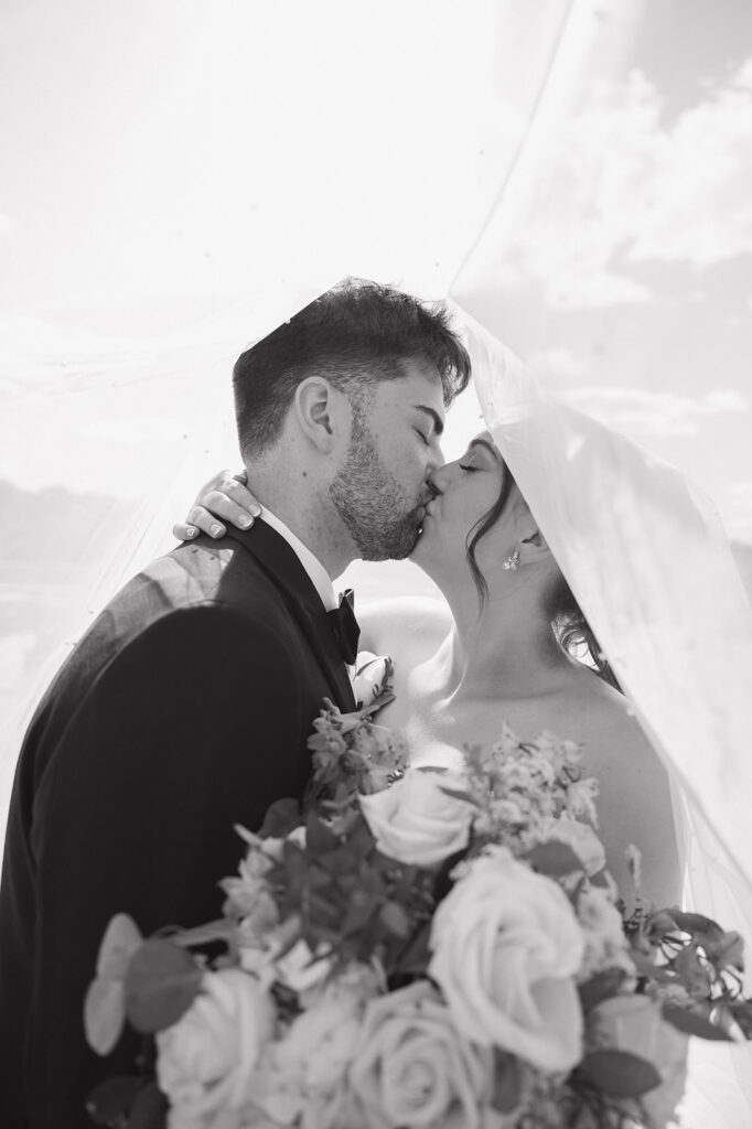 Black and white photo of a bride and groom kissing during portraits.