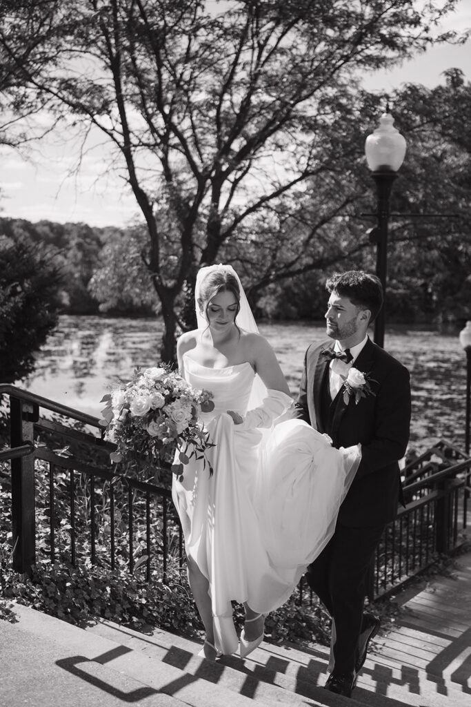 Black and white photo of a bride and groom walking up the stairs at Kellogg Park in Plymouth, Michigan.