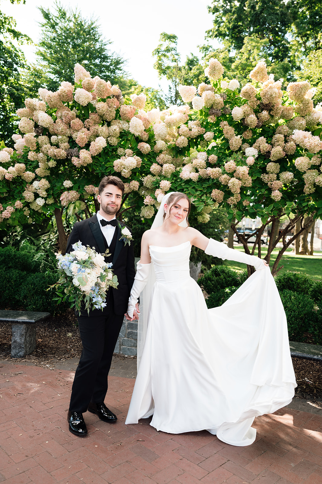 Bride and groom posing in front of a floral bush at Kellogg Park in Plymouth.