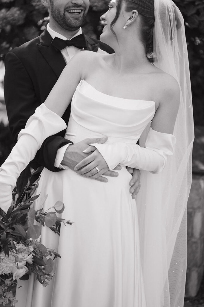 Close up black and white photo of a bride and groom embracing.