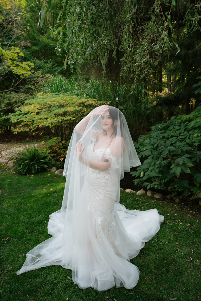 Bride posing under her veil for her Everlastings in the Wildwood wedding portraits.