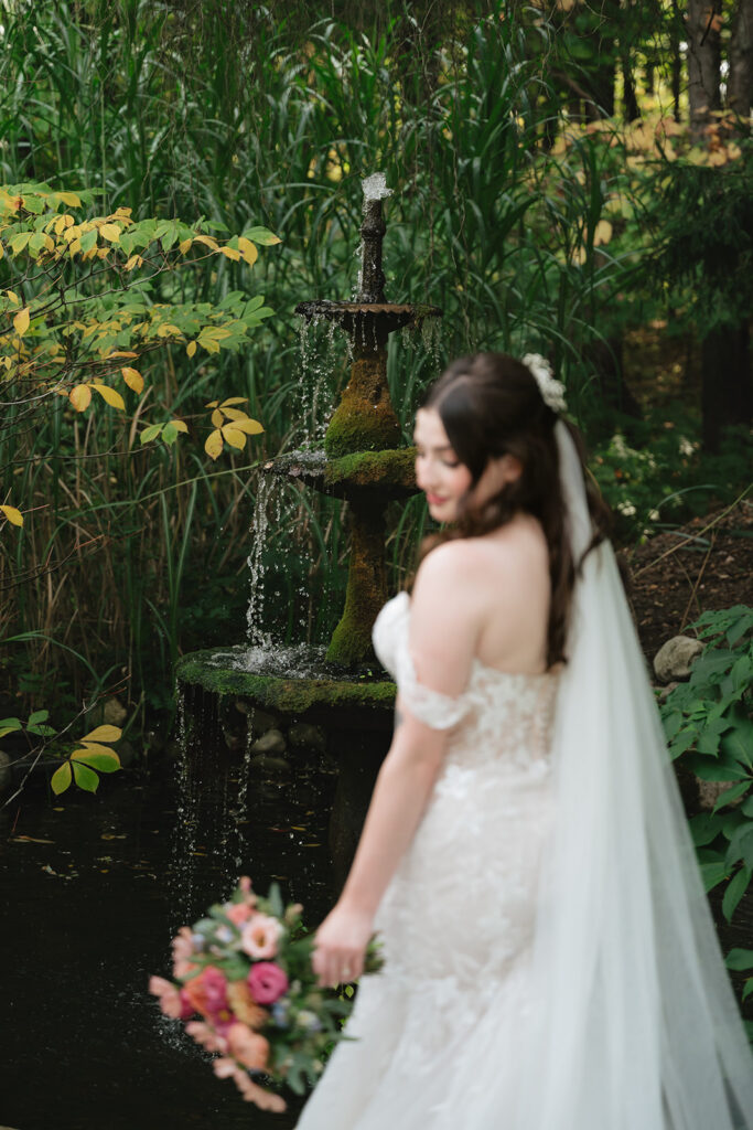 Bride posing in front of a water fountain for her Everlastings in the Wildwood wedding portraits.