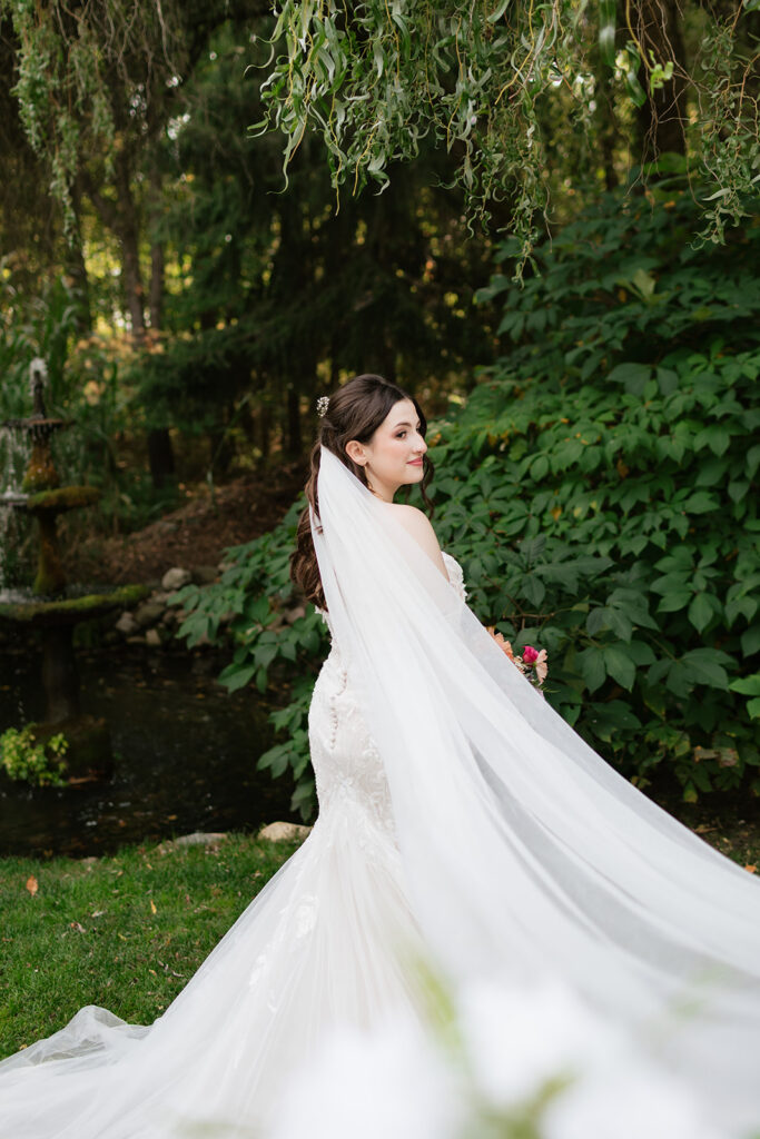 Bride wearing a lace wedding dress and long veil during garden portraits at Everlastings in the Wildwood.