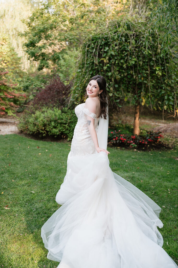 Bride looking back at the camera and playfully holding the train of her dress. 