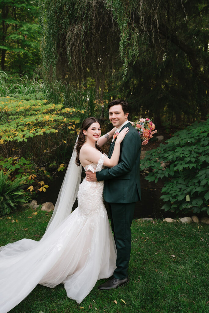 Bride and groom smiling at the camera during their Everlastings in the Wildwood wedding photos. 