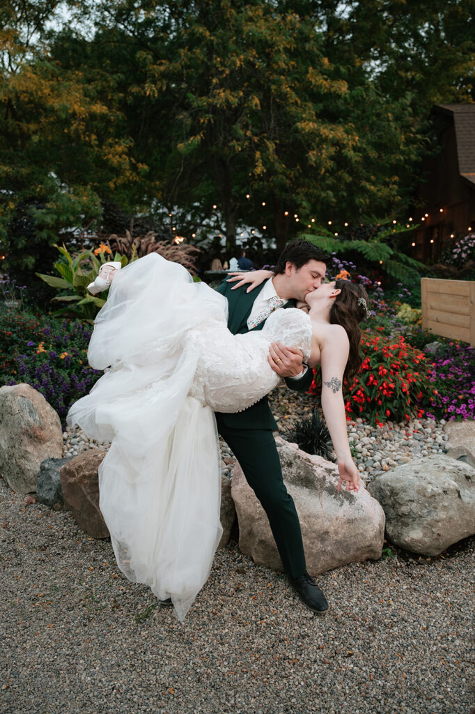 Groom lifting and dipping the bride for a kiss during their Everlastings in the Wildwood wedding photos in Owosso, Michigan.