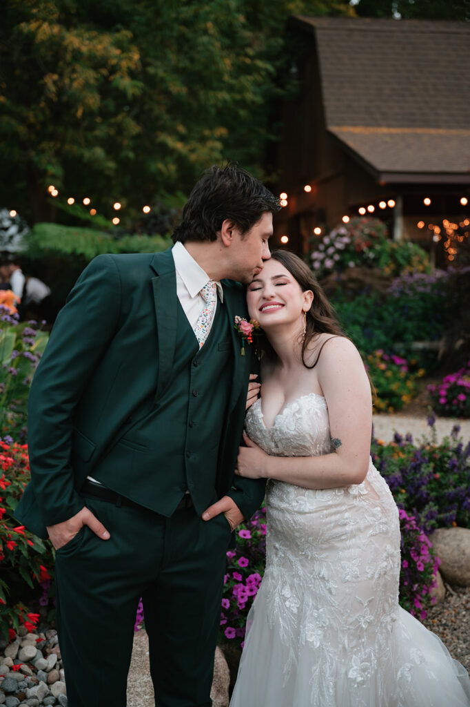 Groom kissing the bride’s forehead during garden wedding portraits in Owosso, Michigan.