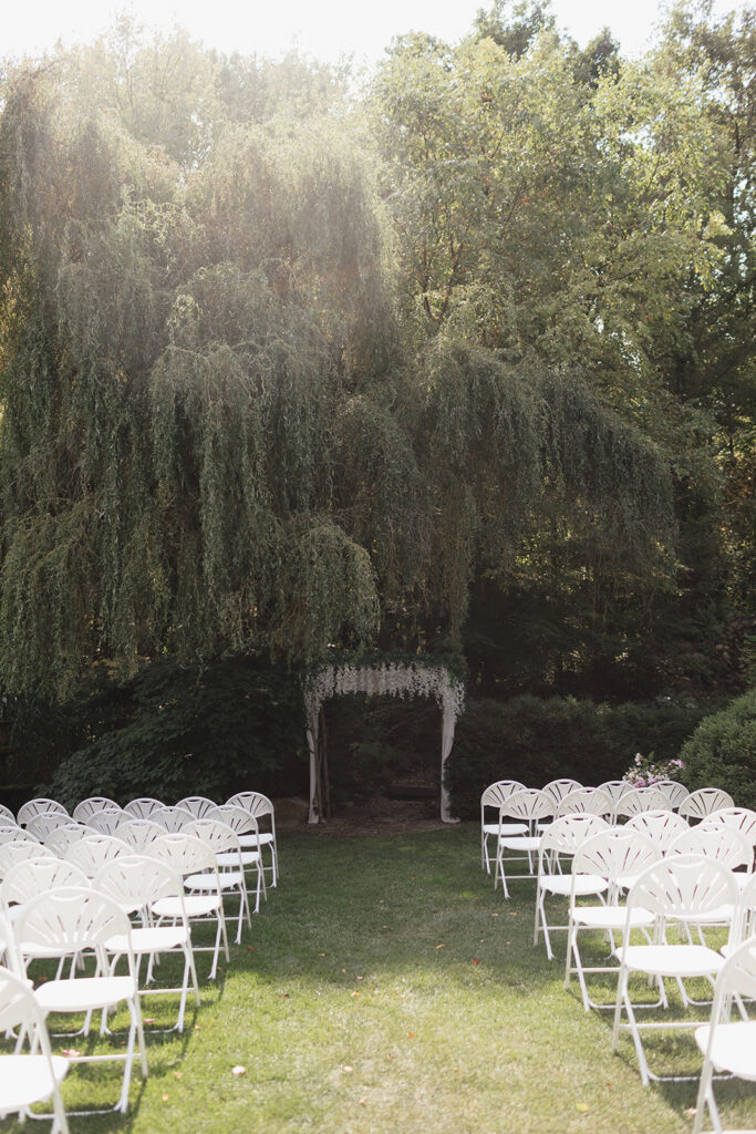 Outdoor wedding ceremony setup beneath a large willow tree at Everlastings in the Wildwood.