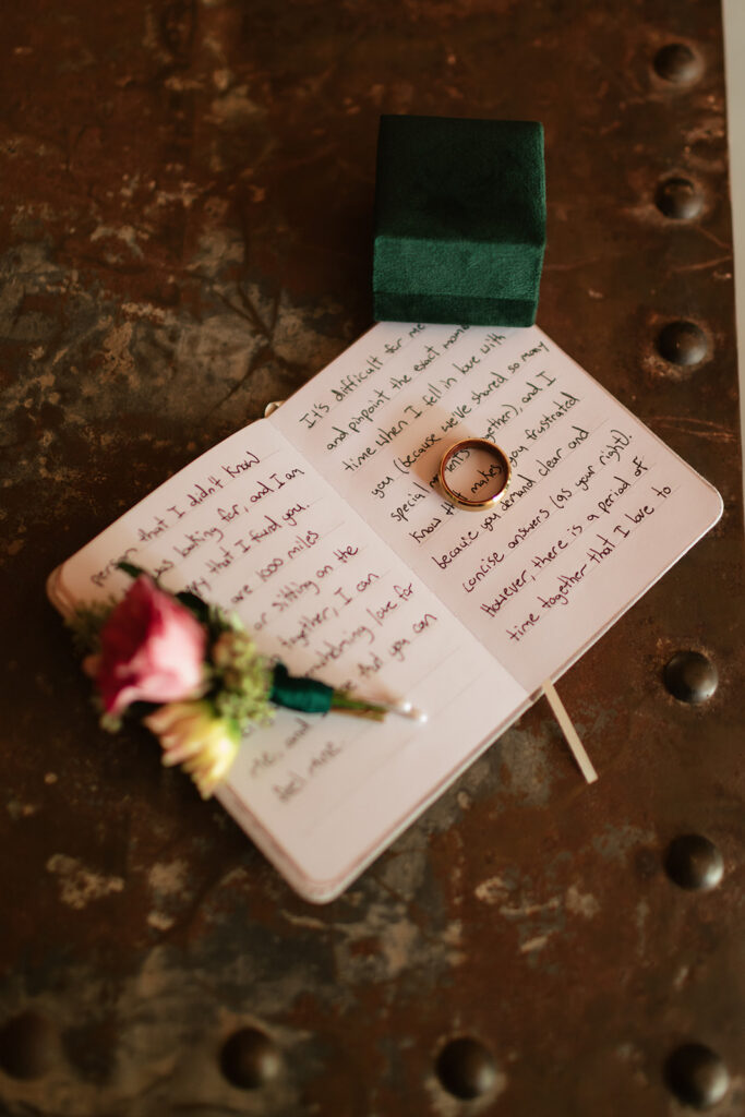 Vow book with the grooms wedding band, boutonniere, and ring box. 