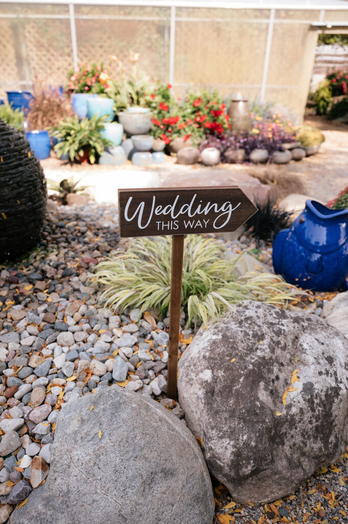 Sign in a garden that says wedding this way.