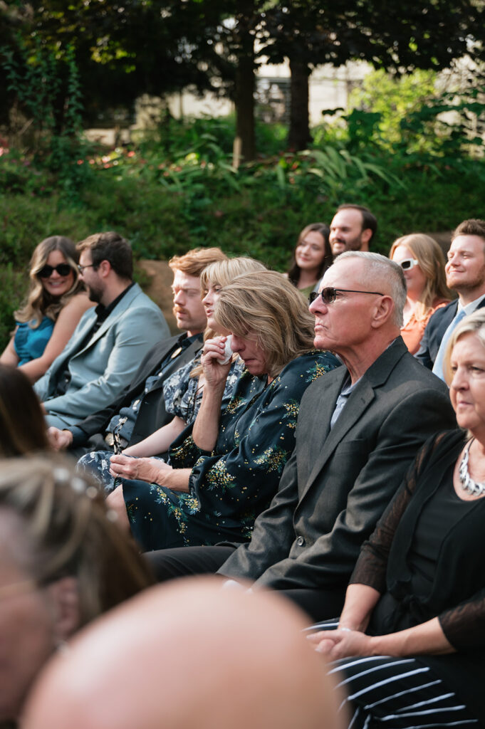 Emotional wedding guests watching an outdoor ceremony at Everlastings in the Wildwood.