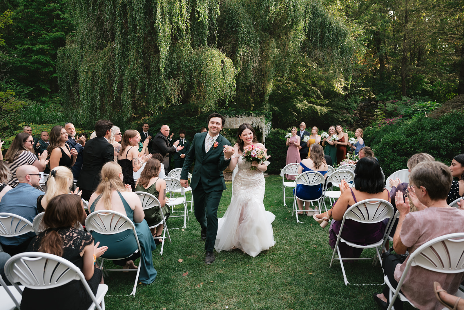 Newlyweds walking back down the aisle as guests applaud after the ceremony.