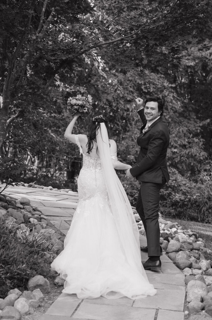 Black and white photo of a bride and groom walking back down the pathway as husband and wife after their ceremony.