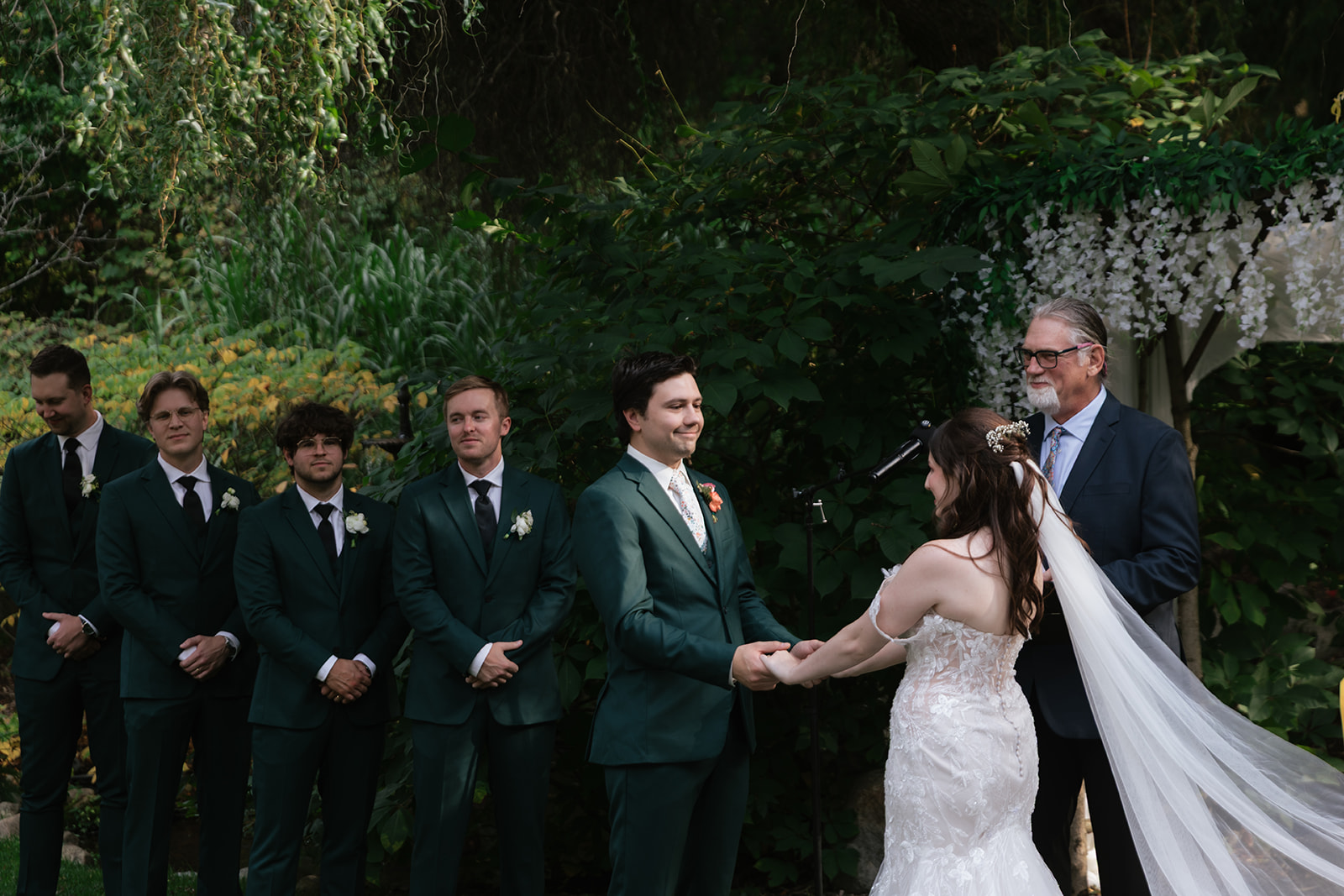 Bride and groom holding hands during their outdoor garden wedding ceremony.