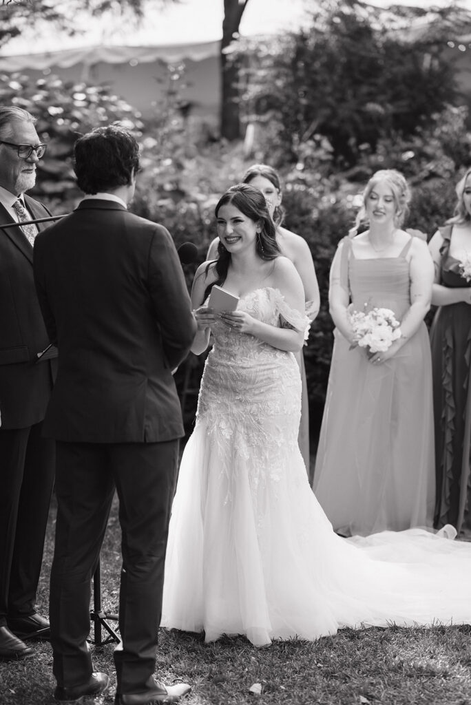 Black and white photo of a bride smiling at the groom during their ceremony.