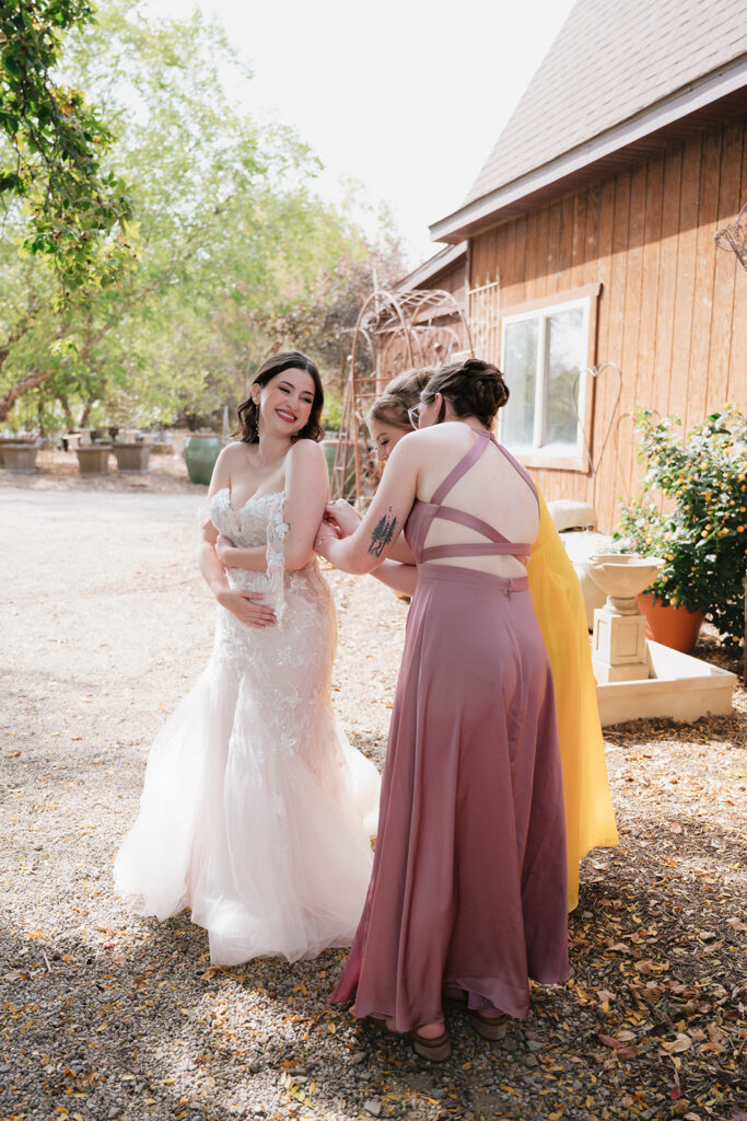 Bridesmaids helping sew up the brides wedding dress before her first look.