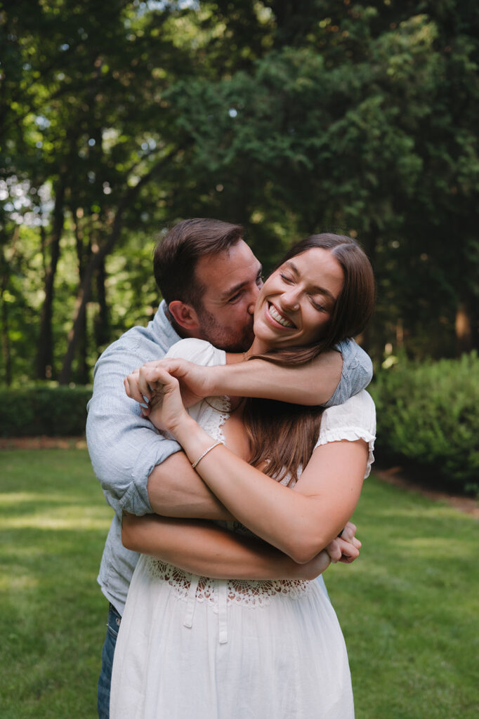 Couple laughing together on a lawn surrounded by trees in Grand Rapids.