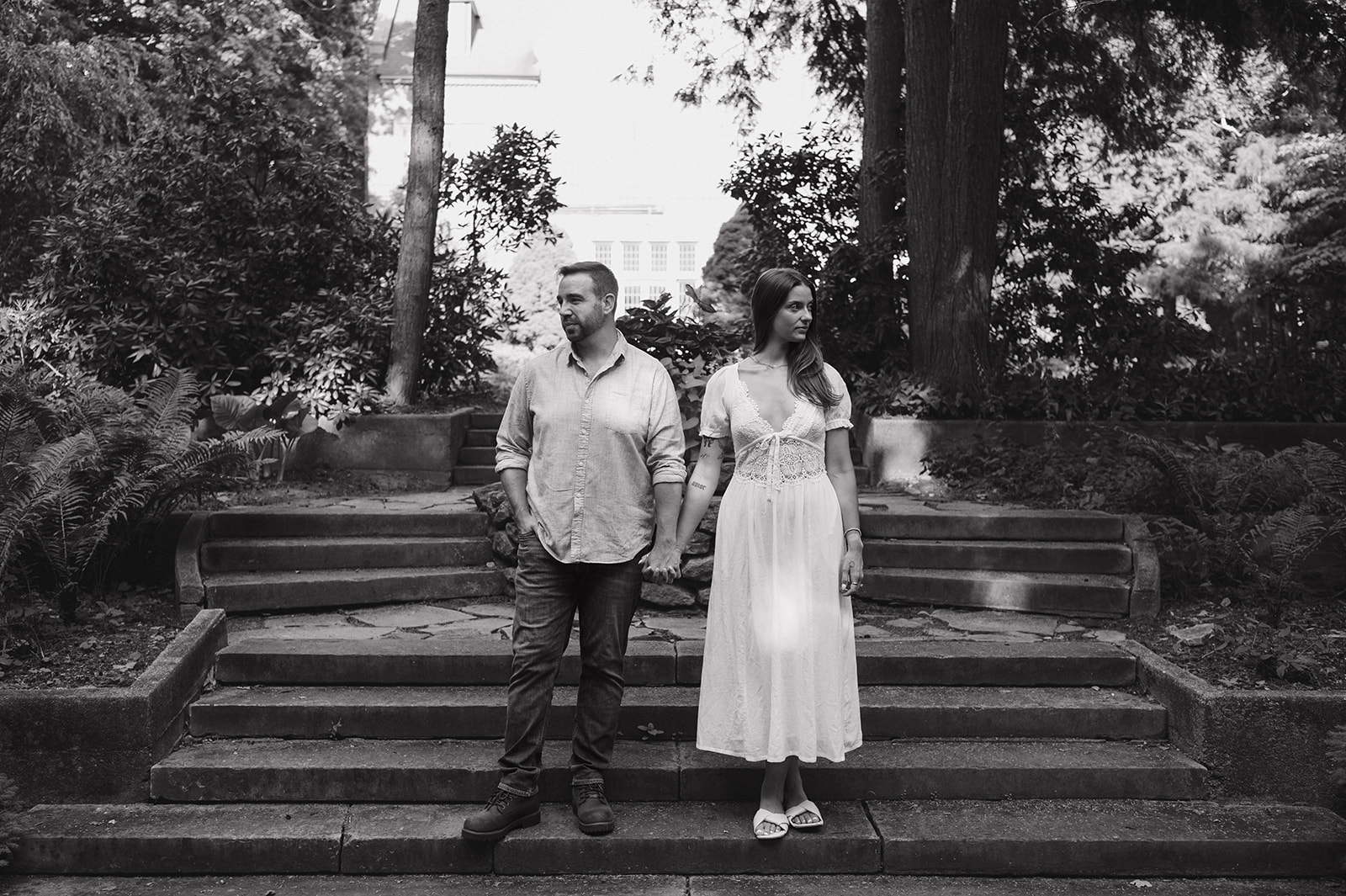 Black and white photo of a couple posing on stone steps for their Aquinas College Grand Rapids engagement photos.