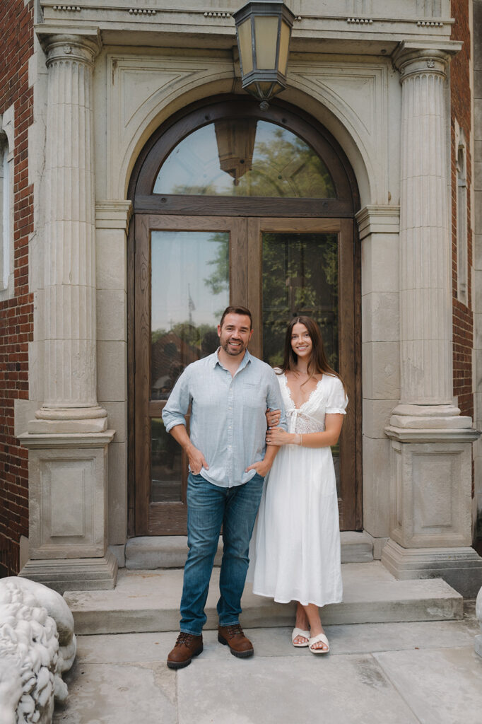 Couple posing in front of an arched wooden doorway at Aquinas College.