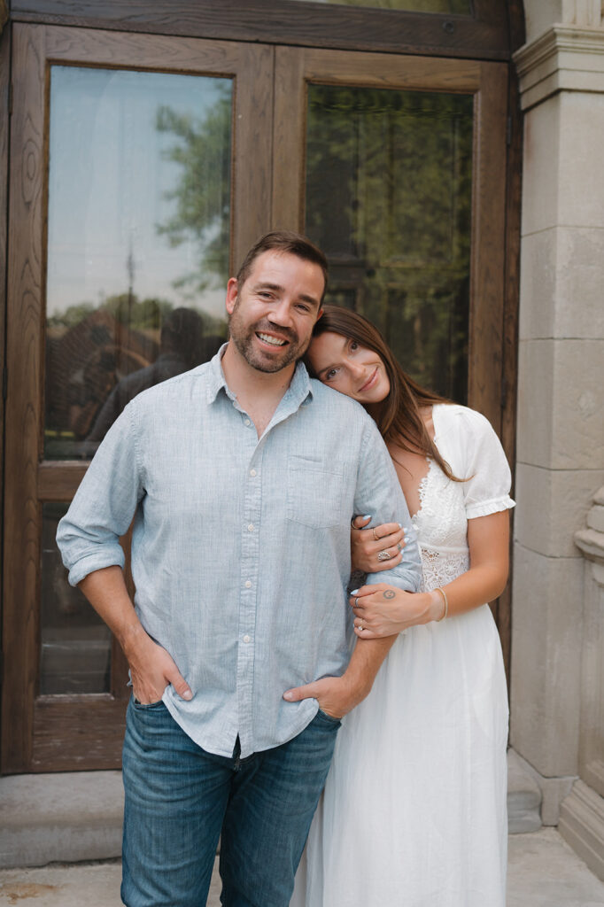 Couple posing in front of an arched wooden doorway at Aquinas College.