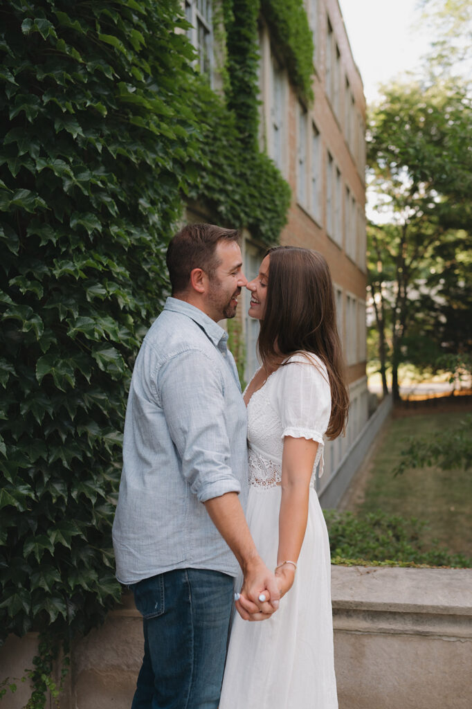 Couple touching noses and smiling during their Grand Rapids engagement photos at Aquinas College.