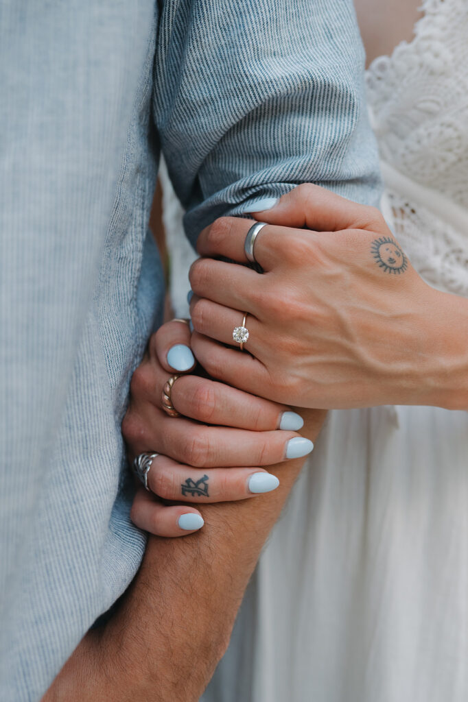 Close up of a woman holding her fiancés arm showing off her ring. 