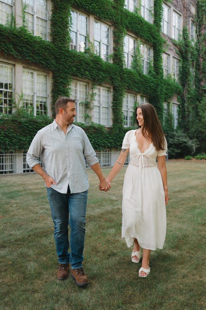 Couple walking hand in hand in front of Aquinas College in Grand Rapids, Michigan.