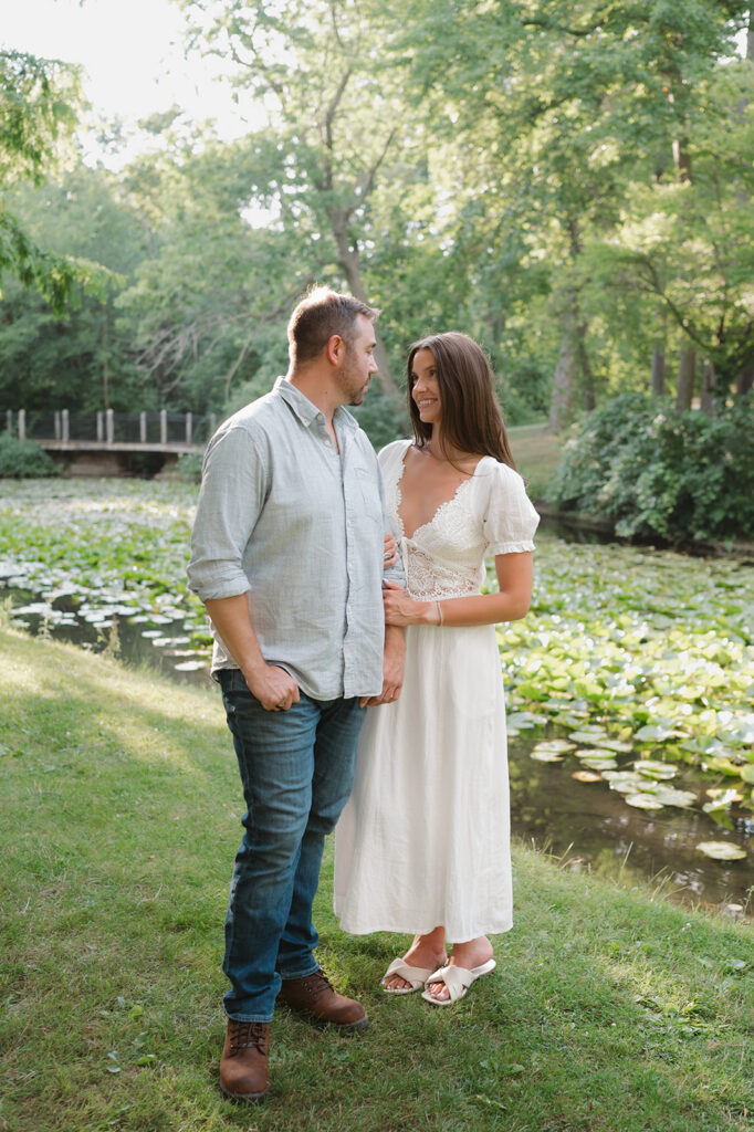 Couple posing together beside a lily pond during their engagement session.