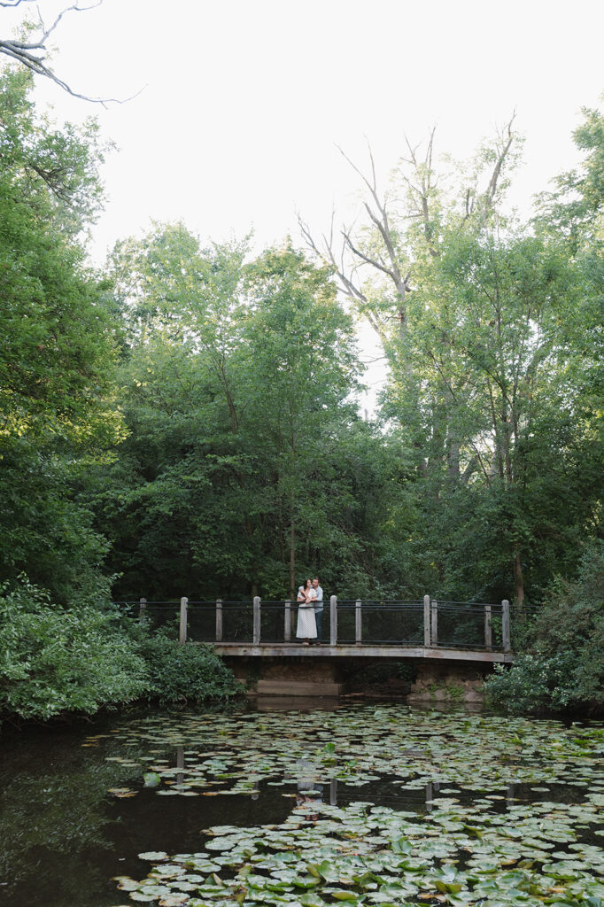 Couple posing on a bridge over a lily pond during their Grand Rapids engagement photos.