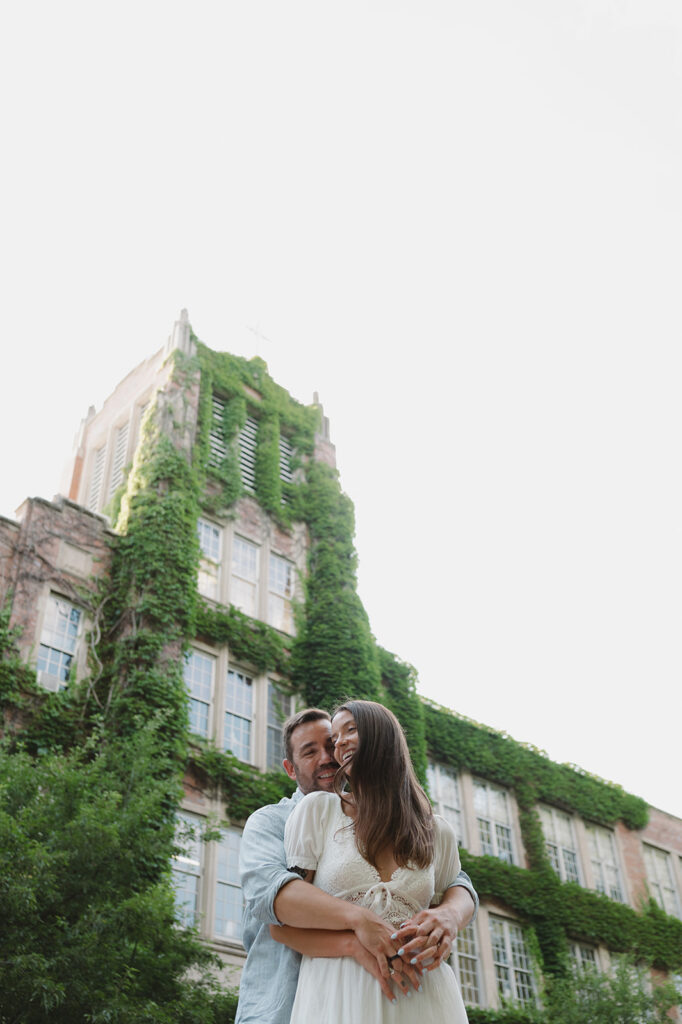Couple laughing beneath an ivy-covered campus building in Grand Rapids.