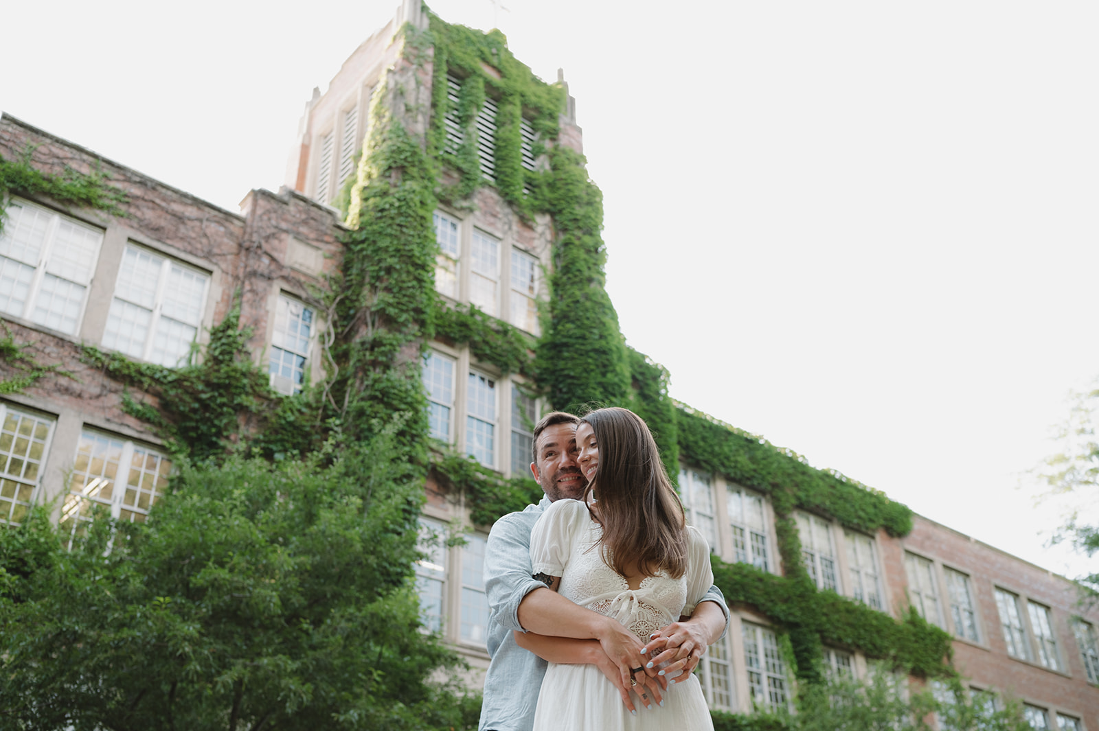 Couple laughing beneath an ivy-covered campus building in Grand Rapids.