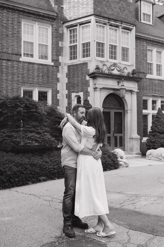 Black and white photo of a couple embracing for their Grand Rapids engagement photos in front of Aquinas College.